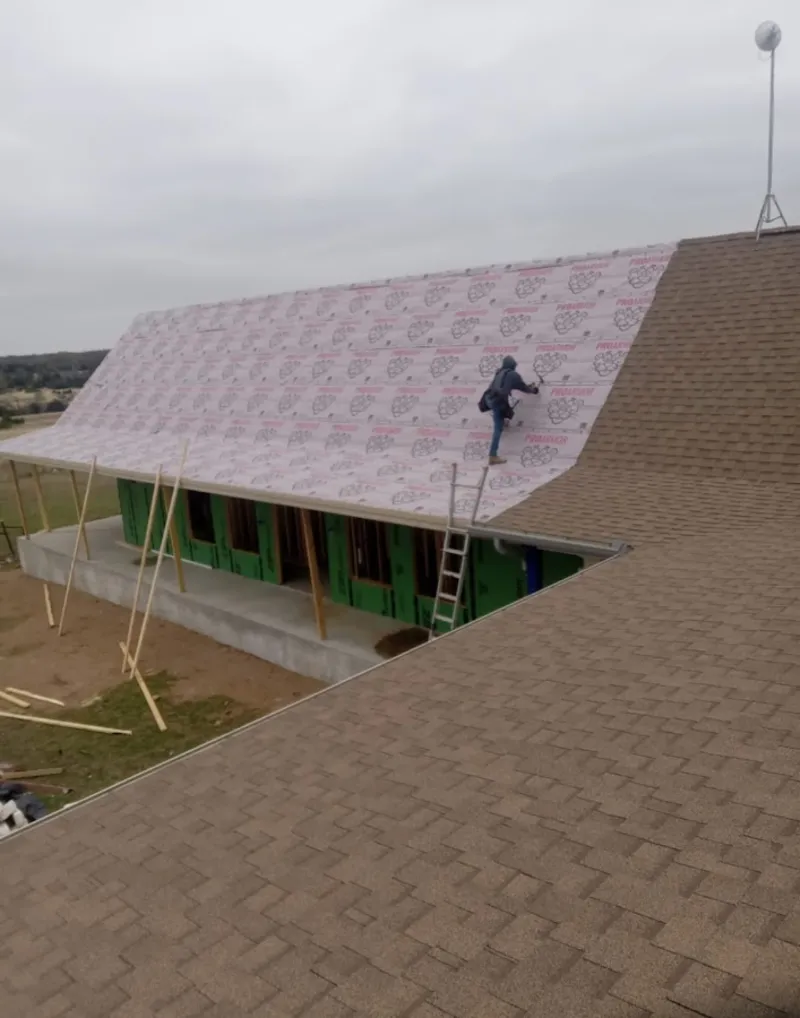 Worker preparing underlayment for a metal roof installation in Park